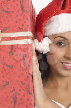 Woman wearing a Santa hat and holding a Christmas present
