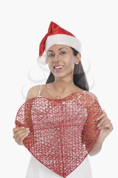 Woman wearing a Santa hat and holding a heart shape object