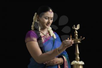 South Indian woman lighting an oil lamp