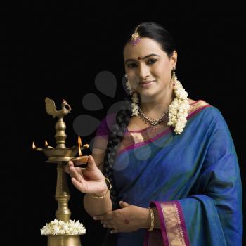 South Indian woman lighting an oil lamp
