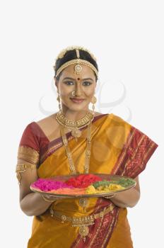 South Indian woman holding a tray of powder paints for rangoli