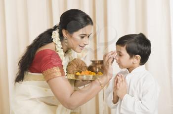 Woman applying tilak to her son