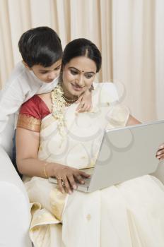 Woman using a laptop with her son standing behind her
