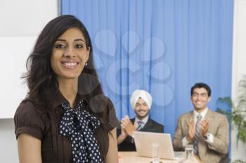 Businesswoman smiling with her colleagues in the background