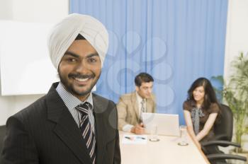 Businessman smiling with his colleagues in the background