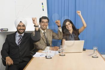 Business executives raising hands in an office