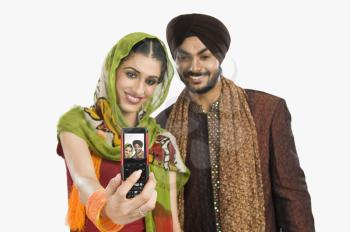 Sikh couple taking a picture of themselves with a mobile phone