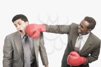 Businessman punching his co-worker with boxing gloves