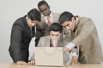 Four businessmen working on a laptop