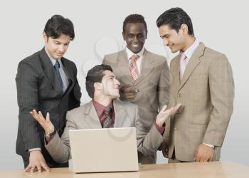 Four businessmen in front of a laptop