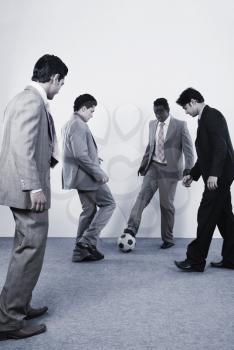 Four businessmen playing with a soccer ball