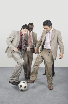 Four businessmen playing with a soccer ball