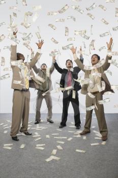 Banknotes falling over four businessmen
