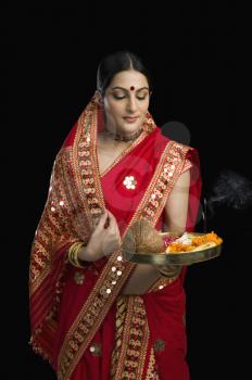 Woman in bright red mekhla holding religious offering