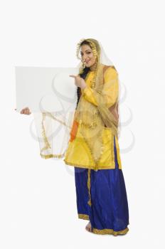 Woman in traditional Punjabi dress holding a placard
