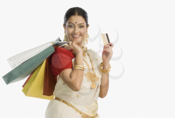Woman in traditional South Indian sari holding shopping bags with a credit card and smiling
