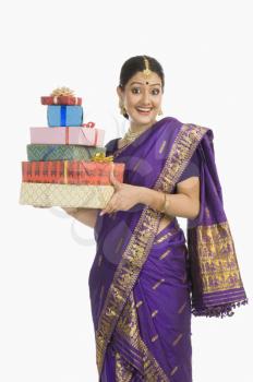 Portrait of a woman in traditional Assamese dress holding gifts and smiling