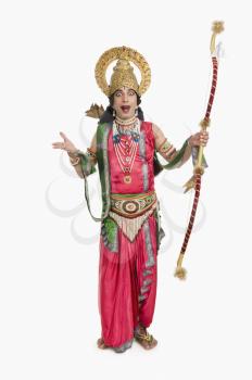 Portrait of a stage artist dressed-up as Rama the Hindu mythological character and holding a bow and arrow
