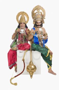 Two stage artists dressed-up as Rama and Ravana and drinking tea