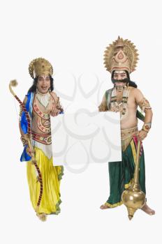 Two men dressed-up as Rama and Ravana and holding a blank placard