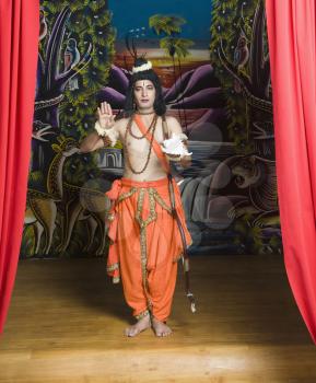 Stage artist dressed-up as Rama blessing and holding a conch shell