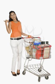 Woman standing with a shopping cart and pointing