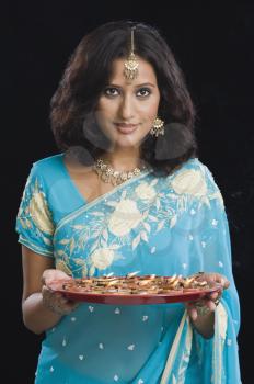 Woman holding a traditional Diwali thali and smiling