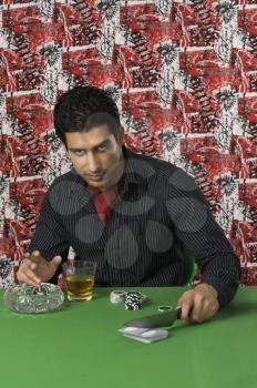 Man smoking and drinking at a casino table