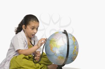 Girl examining a globe with a stethoscope