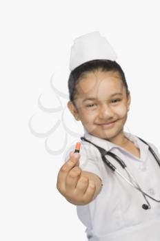 Girl dressed as a nurse and holding a capsule and smiling