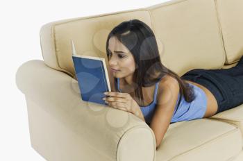 Woman resting on a couch and reading a book