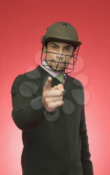 Portrait of a businessman wearing a cricket helmet and pointing