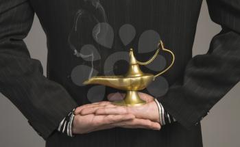 Mid section view of a businessman holding a magic lamp