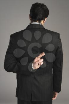Businessman with fingers crossed behind his back