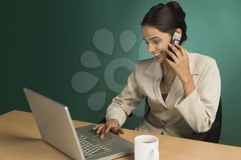 Businesswoman using a laptop and talking on a mobile phone