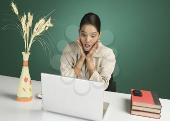 Businesswoman using a laptop and looking surprised