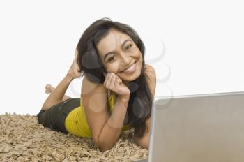 Woman lying on a rug and working on a laptop