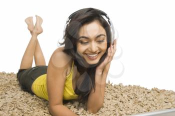 Woman lying on a rug and listening to music on headphones