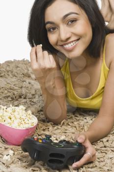 Portrait of a woman eating popcorn and playing video game