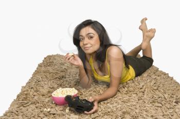 Portrait of a woman eating popcorn and playing video game