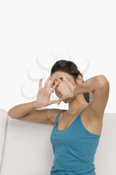 Woman sitting on a couch and covering her face with her hands