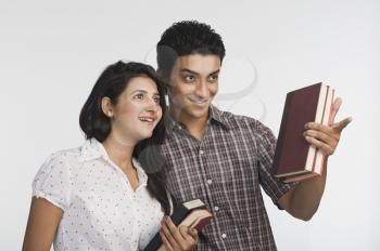 College students holding books and smiling