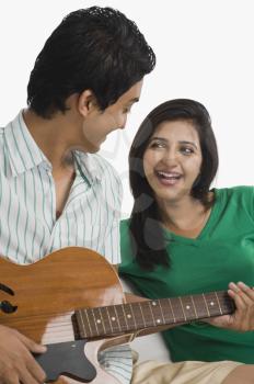 Man playing a guitar beside a woman