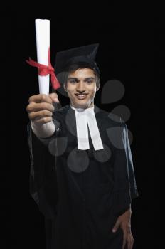 Portrait of a man in a graduation gown holding a diploma