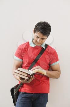 Man leaning against a wall and reading a book