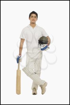 Portrait of a cricket batsman standing with a bat and a helmet