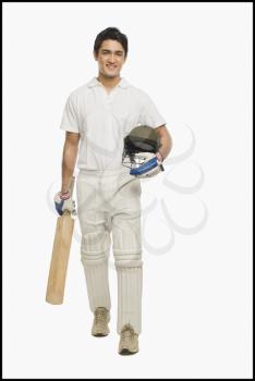 Portrait of a cricket batsman walking with a bat and a helmet