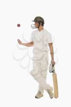 Cricket batsman tossing a cricket ball