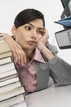 Stack of books in front of a businesswoman at desk