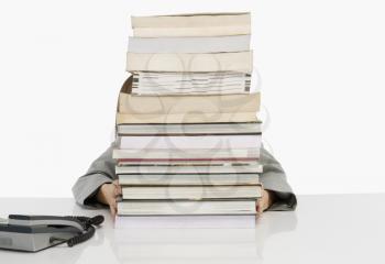 Business person hiding behind a stack of books